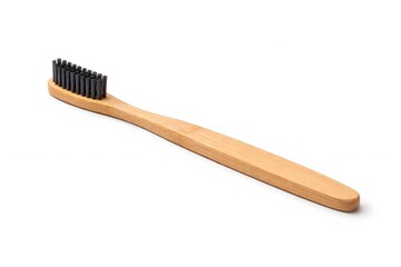 Natural wooden bamboo toothbrush with black bristles positioned diagonally on a clean white background on white background