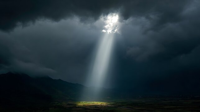 Dramatic sunbeam breaking through dark storm clouds over a lush green mountain valley
