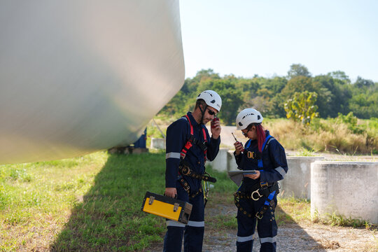 An engineer carefully examines a wind turbine blade at a construction site, placing a large blade on the ground to highlight the renewable energy technology.