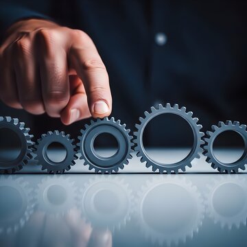 Hand adjusting metal gear on table representing change management transformation, strategy alignment, process optimization and leadership intervention.  Photo | copy space 