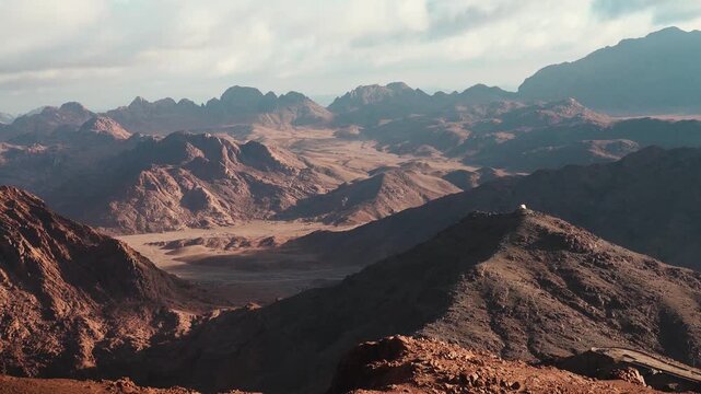 A scenic panorama of the Mousa Mountain features a high desert mountain landscape under a sunset sky with clouds on sinai saint catherine egypt