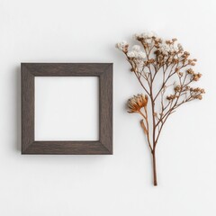 Minimalist flat lay dark wood frame beside delicate dried floral sprig