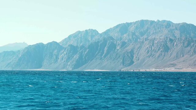 A panoramic blue nature landscape of ocean and mountain under a cloudy sky on a red sea dahab