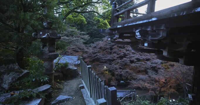 Narrow path behind ancient Japanese temple with old stone lanterns - locked off shot