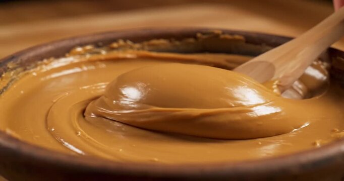 Creamy peanut butter being stirred in a rustic bowl, showcasing its smooth texture and rich color