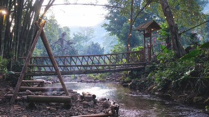 A canal flowing down under wooden bridge in the forest © Farknot Architect
