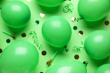 Many air balloons with party whistles and confetti on green background