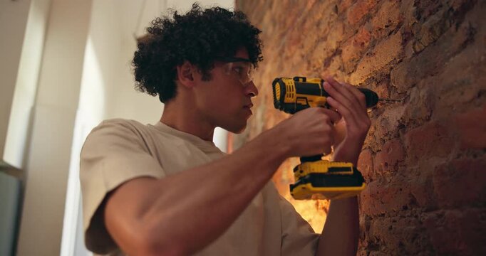 Brick wall, man and drill in home for renovation, DIY or maintenance with repair. Equipment, person and electric machine for drilling, house upgrade or improvement with safety goggles for remodeling