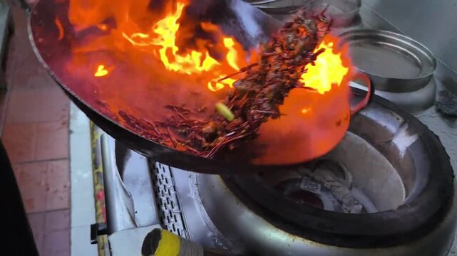 A chef is stir-frying Chinese food over high heat	
