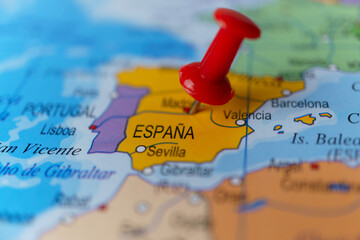 Red pushpin pointing to spain on a political world map, highlighting madrid and the iberian peninsula as a travel destination © JOSEANTONA
