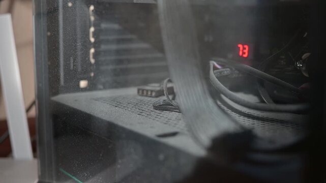 A close-up of a dirty computer case with various hardware components covered in dust. The display shows the temperature
