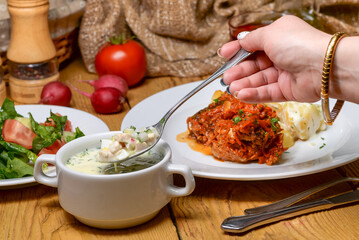 Hand scooping a hearty soup from a bowl at a rustic dining table