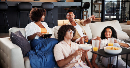 Couple of friends, excited and relax with watching tv on sofa for sport game, point or snack in living room. People, happy and drinks on couch for talk, subscription and television in lounge at home © EineroLens25/peopleimages.com