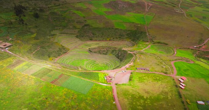 Arcing aerial view of circular terraced bowl of Moray inca ruins in Peru