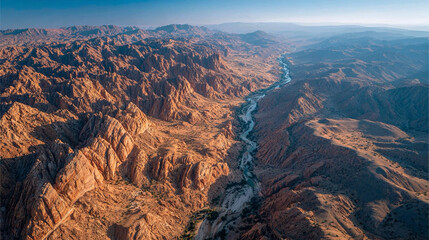 Desert canyon aerial, textured rock walls and valley floor, sunlight casting shadows, emphasizing geological patterns, natural textures, and dramatic desert landscape.