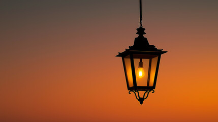 Obraz premium Glowing hanging lantern against warm sunset sky creating peaceful evening atmosphere with soft light,