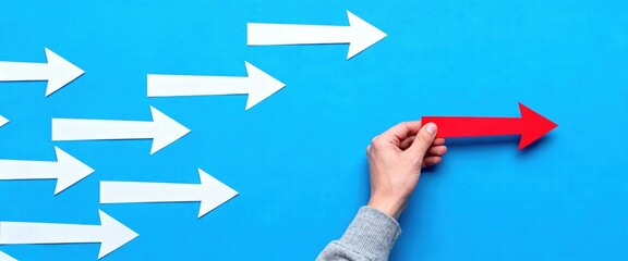 Hand Choosing Red Arrow from White Arrows on Blue Background
