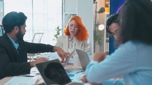 Multi-ethnic business team in office meeting, reviewing documents and brainstorming innovative ideas for a new business venture and strategy.