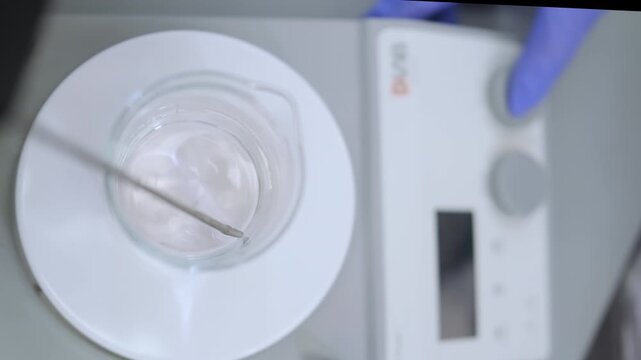 Overhead view of laboratory beaker with solution on magnetic stirrer.