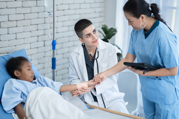 Obraz premium Caucasian female doctor and nurse taking care of little African American girl in hospital room