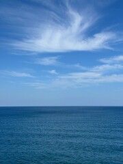 Blue calm sea and blue sky with cirrus clouds vertical.