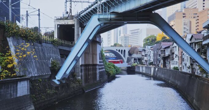 Train crossing canal in Japanese city - wide shot