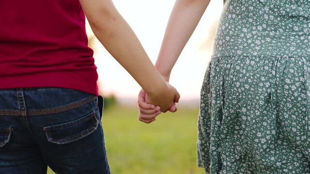 Two kids holding hands in sunset, showing friendship and trust, Close-up of friends walking together, hand in hand at dusk, Childhood memories created while holding hands during golden sunset