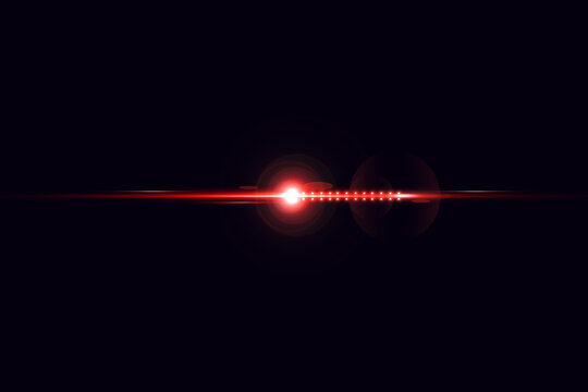 A red laser beam shoots out from a bright light in a dark room