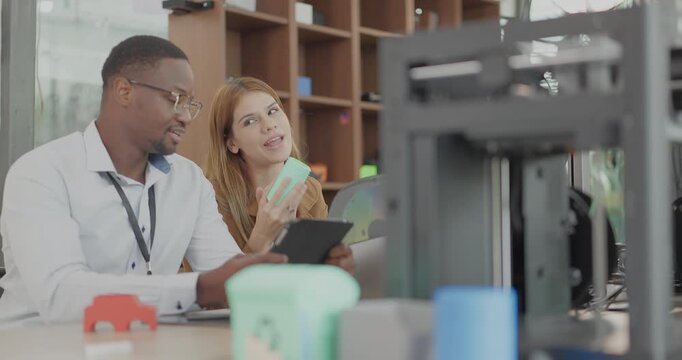 A diverse team of startup professionals collaborates on a 3D printing project in a modern workspace. Highlighting innovation, teamwork, and the prototyping process in a creative tech environment.
