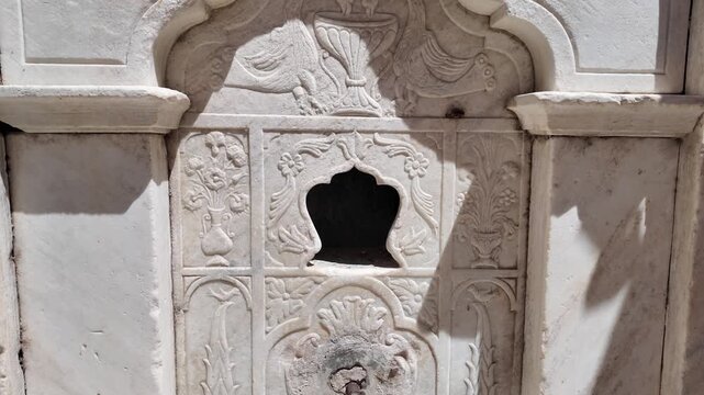 Paros Island,Tilt up of a historic fountain at Paroikia on a sunny day with front details of the marble fountain.