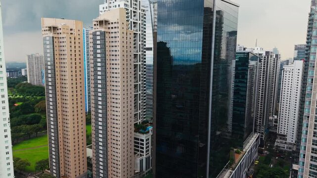 Aerial shot flying toward skyscrapers in Bonifacio Global City under cloudy sky