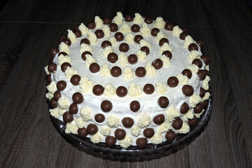 A minimalist homemade white birthday cake with chocolate balls and buttercream peaks, isometric view