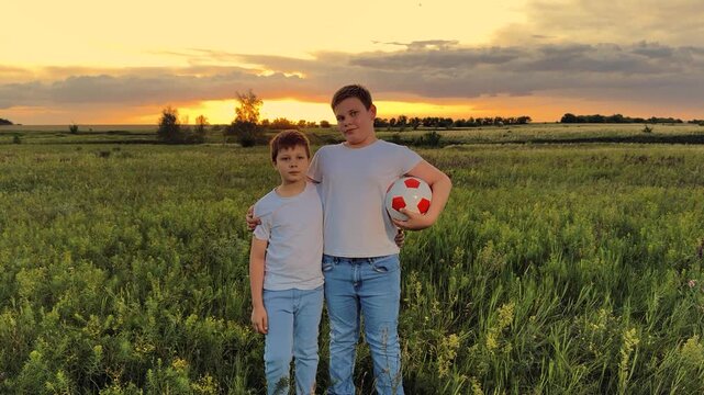 Childhood memories outdoors, boys posing at dusk, soccer as their passion, unity in matching outfits, farmland stretching in the distance, glowing sunshine, arms around shoulders, laughter and