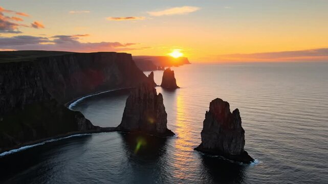 Epic scenic aerial view of dramatic coastal cliffs and sea stacks with a vibrant sunset over the ocean