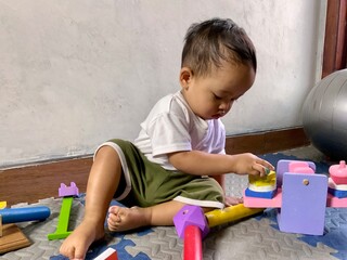 Fototapeta premium Toddler Boy Playing with Wooden Educational Toys on Play Mat at Home