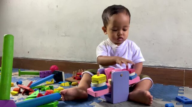 Toddler playing with colorful wooden educational toys on floor mat