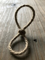 Obraz premium Handcrafted loop with knotted brown natural fiber rests on rustic wood