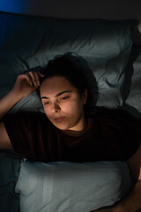 Top view of young woman waking up at night lying sleepless in bed. insomnia and sleep disorder...