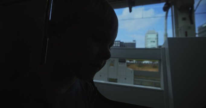 Silhouette closeup of little boy sitting by window of Japanese train