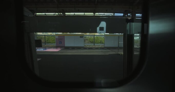 View of tracks and station through moving Japanese train window