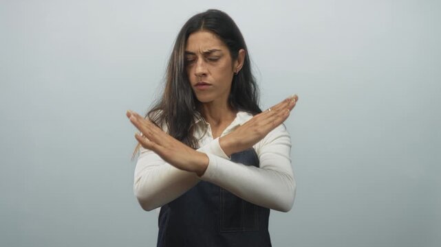 Woman with arms crossed in x gesture in studio with pale blue backdrop; rejection assertiveness boundary.