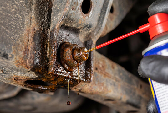 Pumping red lubricating grease into car suspension ball joint with a grease gun