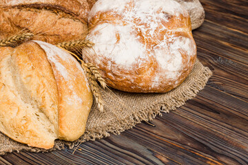 Naklejka premium Homemade natural breads. Different kinds of fresh bread as background, perspective view with copy space