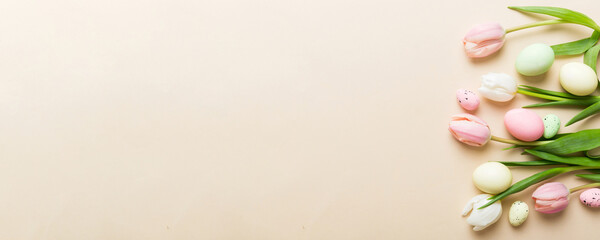 Happy Easter composition. Easter eggs on colored table with yellow Tulips. Natural dyed colorful...