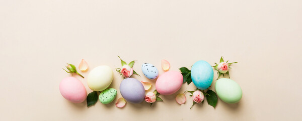 Obraz premium Happy Easter. Easter eggs on colored table with yellow roses. Natural dyed colorful eggs background top view with copy space
