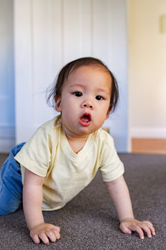 Asian girl crawling on carpeted floor inside home