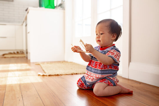 Asian baby girl playing with sunglasses on the wooden floor