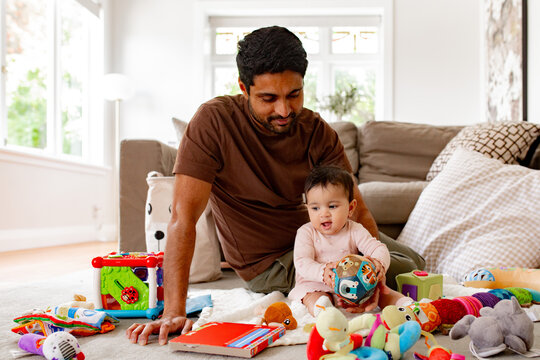 Indian dad playing with baby girl on the carpeted floor