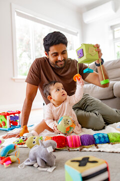 Indian dad playing with baby girl on the carpeted floor