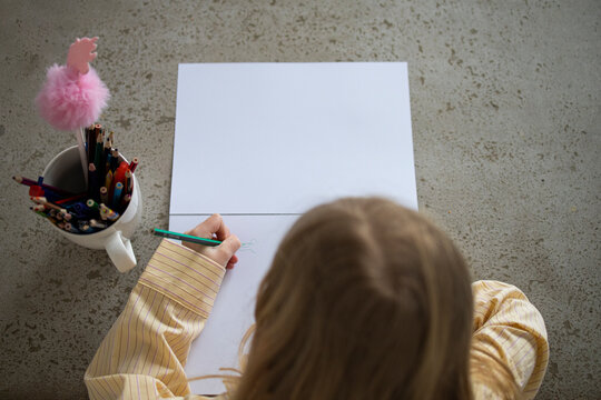 Over Shoulder View of Young Girl Drawing with Pencil at Home.